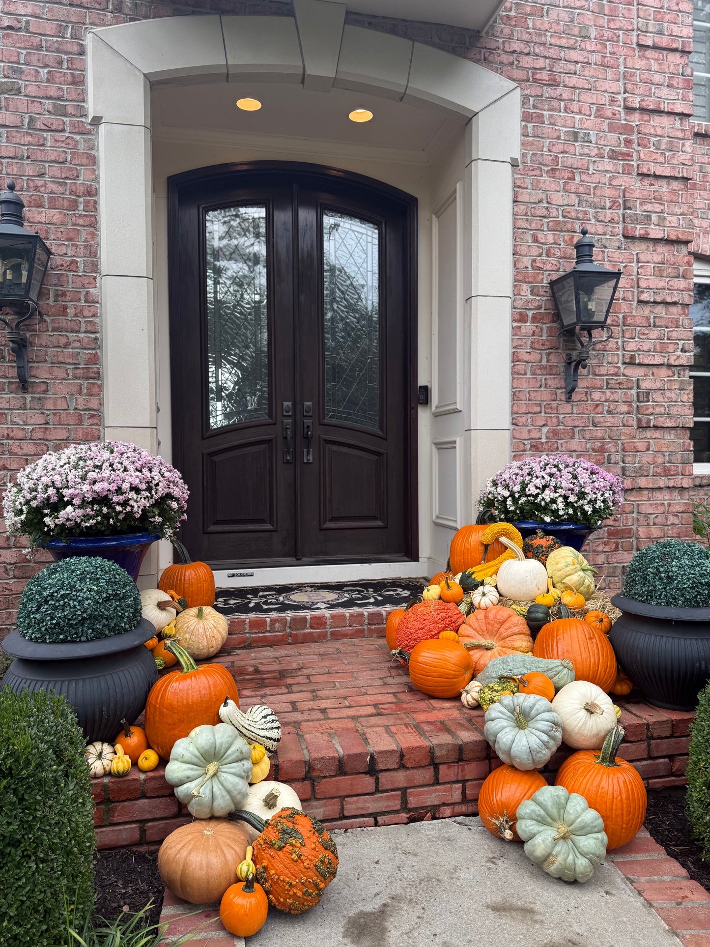 side view of kansas city porch pumpkin arrangement by mum and gourd featuring autumn colors